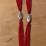 1) Röda plastpärlor med turkos oval medaljong. Total längd ca 47 cm