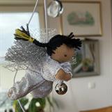 Liten silvrig ängel med svarta flätor och mörk hy