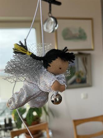 Liten silvrig ängel med svarta flätor och mörk hy