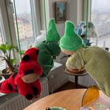 * En knoppdocka har mossgrön kropp och granskottsgrön luva håller i en guldkula