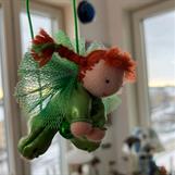 Liten grön skyddsängel med röda flätor
