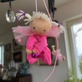 Liten ceriserosa skyddsängel med vita flätor