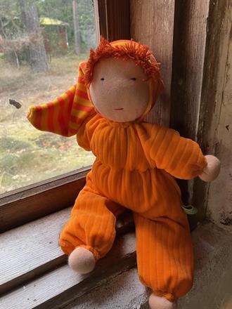 Stor orange kramdocka med randig luva och röd lugg