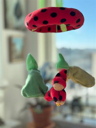* Knyttdockan har dräkt och luva i röd velour med svarta prickar (e.g. nyckelpiga), håller i en guldkula