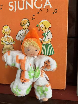 Fickdocka i mönstrad vit velour med med luva och blond lugg