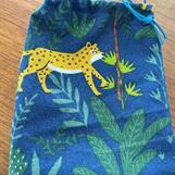 Gula leoparder på blå botten med gröna växter  .  Dockorna har blont, rött och svart hår, den svarthåriga med mörk hy.