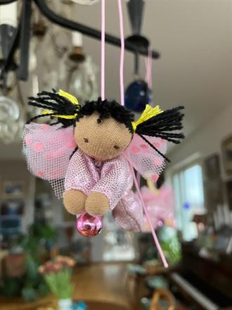 Liten ljusrosa skyddsängel med svarta tofsar o mörk hud