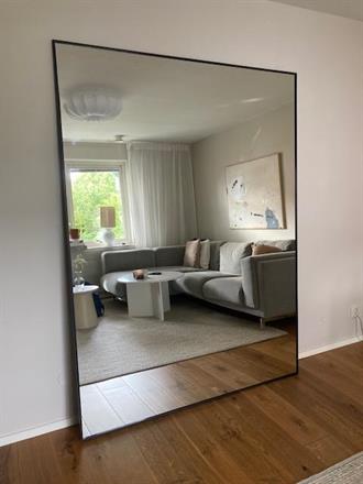 Spegel som står lutad mot väggen i ett vardagsrum